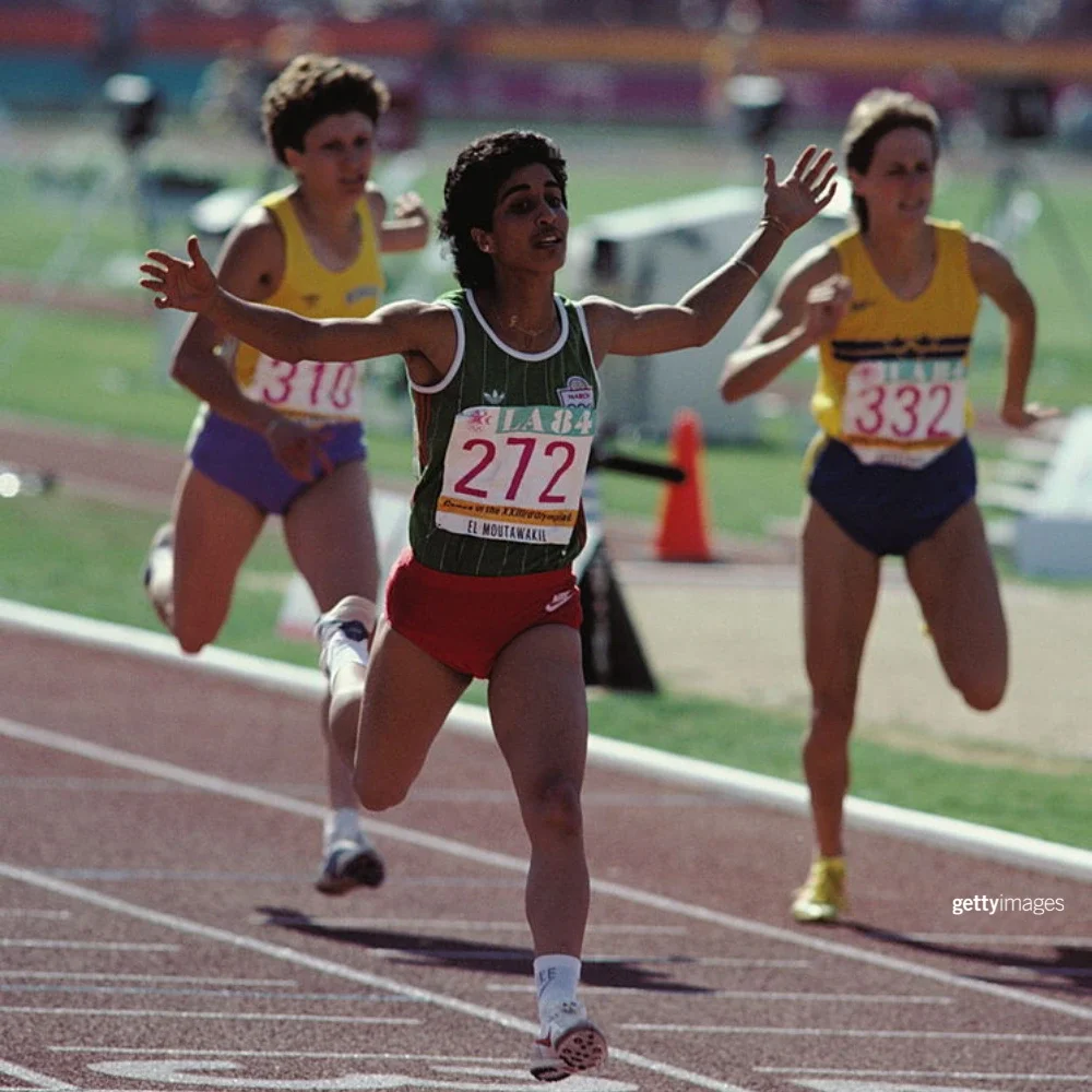 Nawal El Moutawakel raising her hands up after crossing the finish line of the 400m Hurdles Women's event finals.