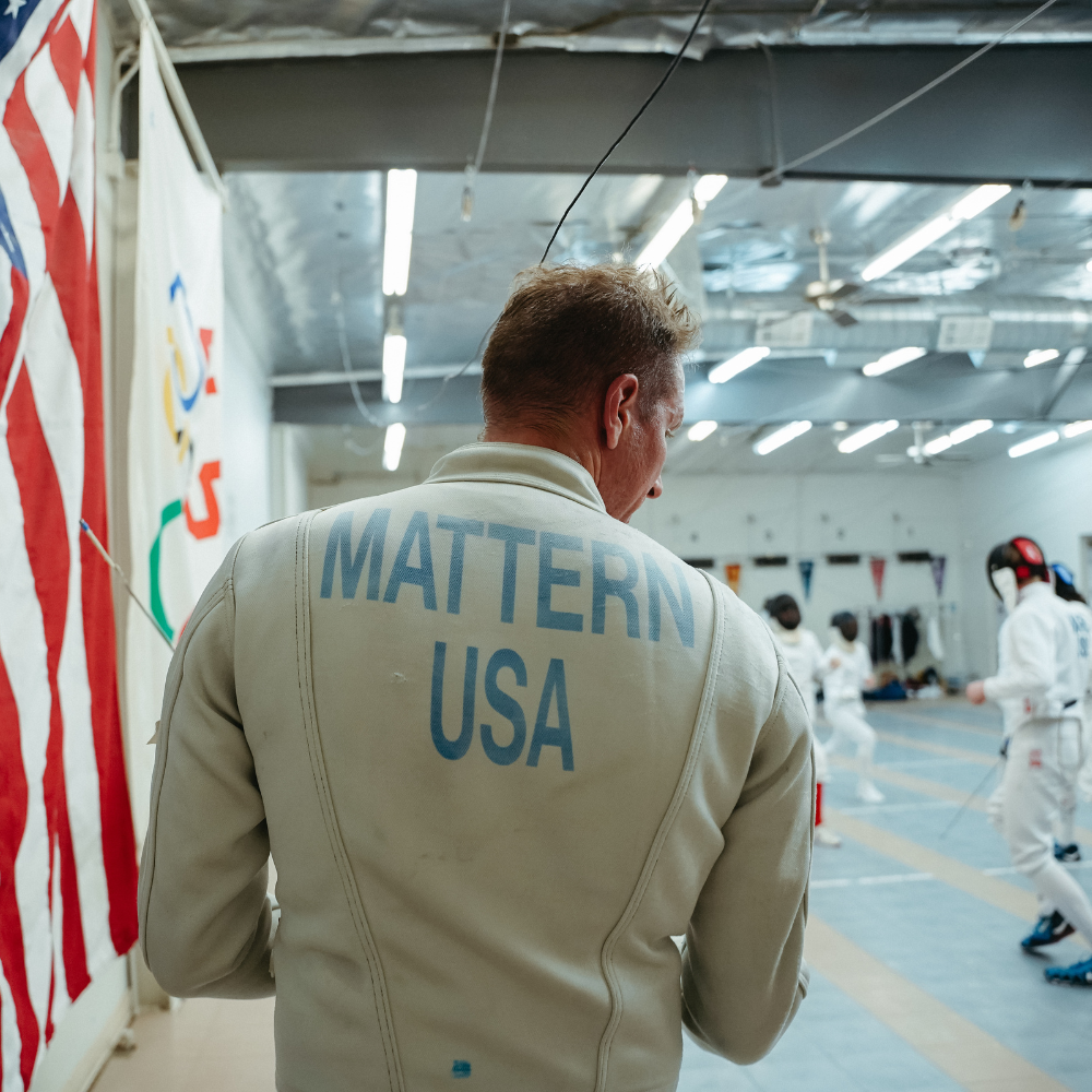 Cody Mattern wearing a fencing jacket with the name 'Mattern' and 'USA' across the back shoulders