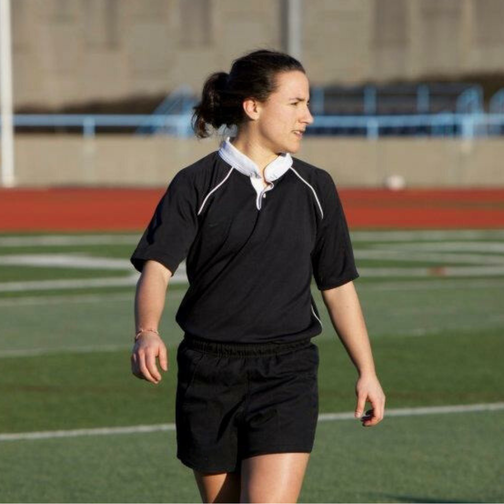 Izzy walking on a rugby field wearing Columbia Univ rugby jersey