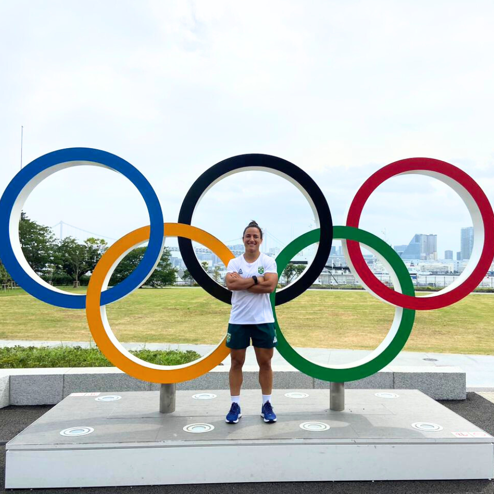 Izzy standing in front of the Olympic rings at Tokyo 2020