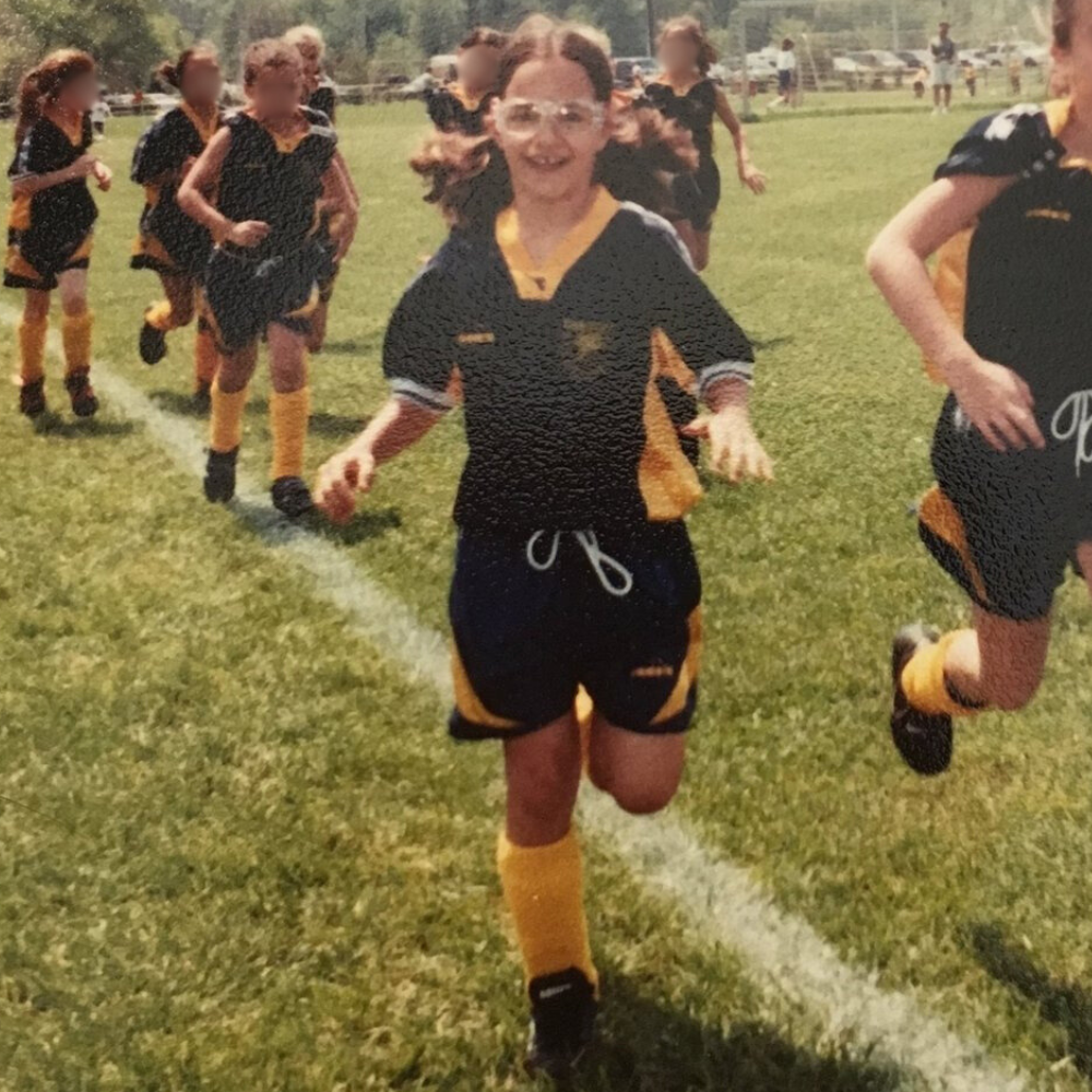 Young Izzy running on a soccer field in a black shorts and jersey