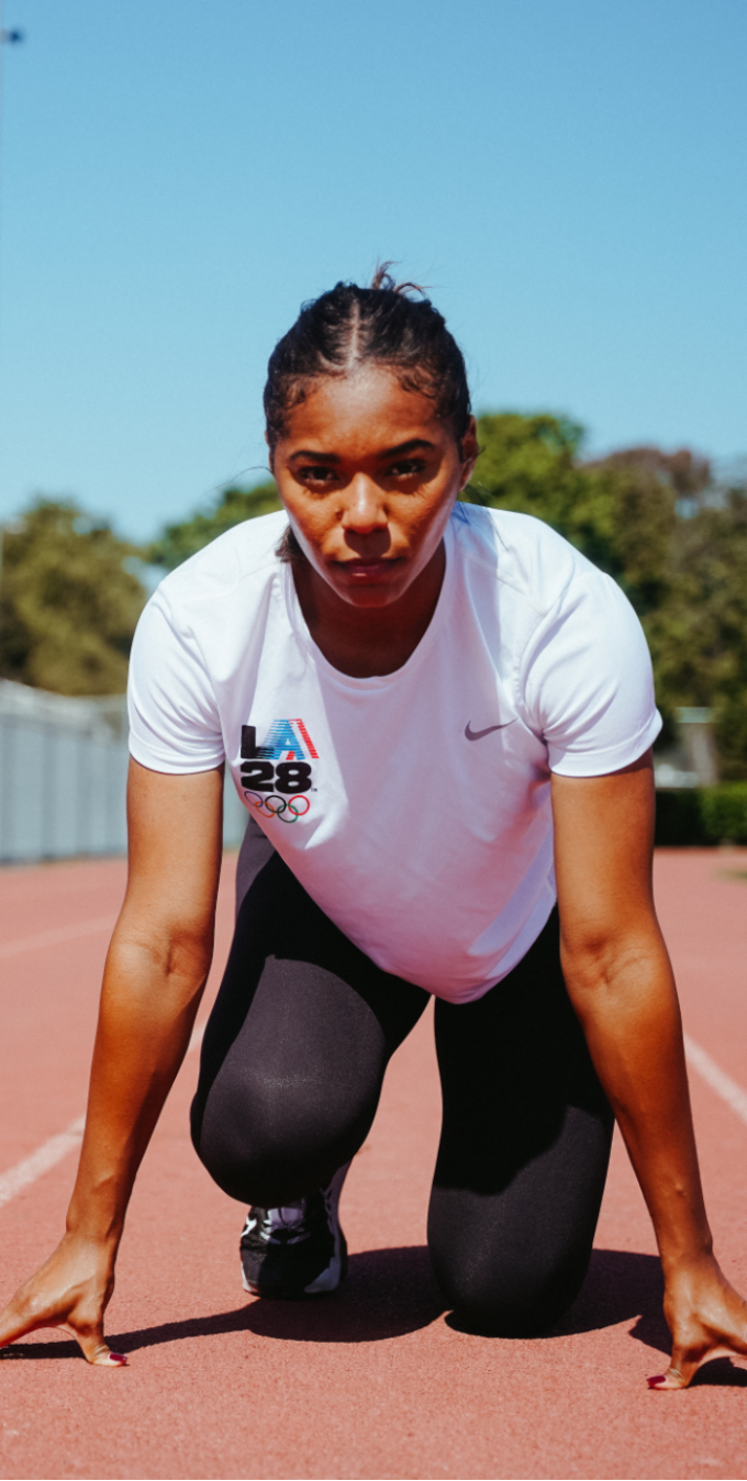 Samantha Dirks in take-off position on a track wearing a white shirt with an LA28 logo and black leggings