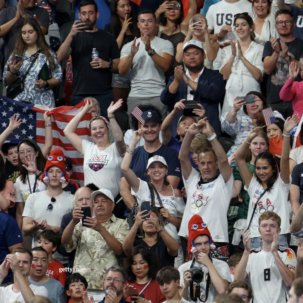 Aficionados animando en las gradas durante los Juegos Olímpicos, muchos de ellos vistiendo ropa del Equipo de Estados Unidos.