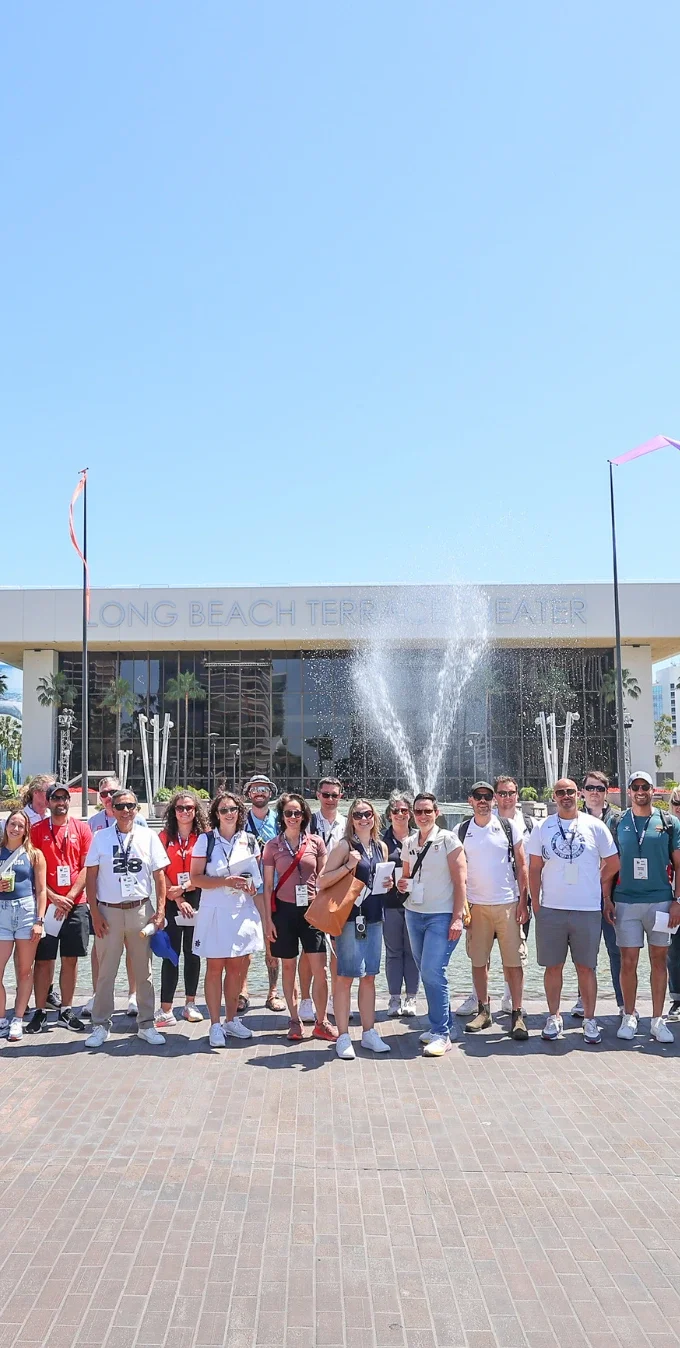 Fotografía de un grupo de miembros del equipo LA28 y delegados internacionales de varios Comités Olímpicos Nacionales frente al Teatro de Long Beach durante la Jornada de Puertas Abiertas 2025 para Comités Olímpicos Nacionales.