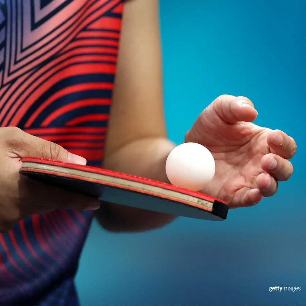 Fotografía de "Un jugador de tenis de mesa sosteniendo una pelota de tenis de mesa con una mano.