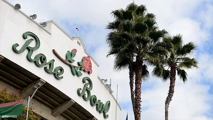 Una fotografía del Rose Bowl Stadium con el logotipo del Rose Bowl en la parte delantera. Delante del estadio, a la derecha de la fotografía, hay un grupo de palmeras.