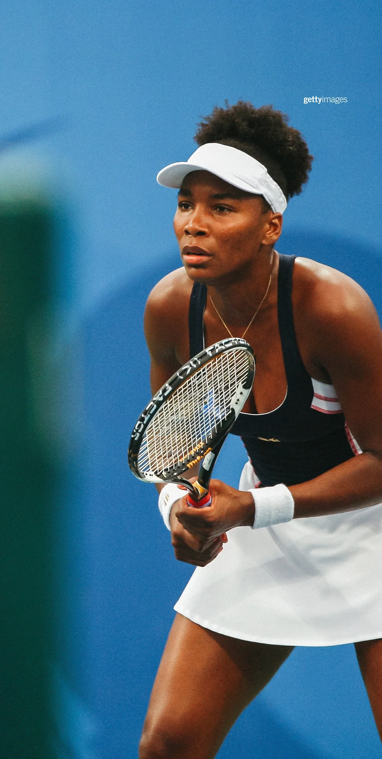 Venus Williams sosteniendo una raqueta de tenis en la cancha mientras se inclina para prepararse para jugar durante los Juegos Olímpicos de Pekín 2008.