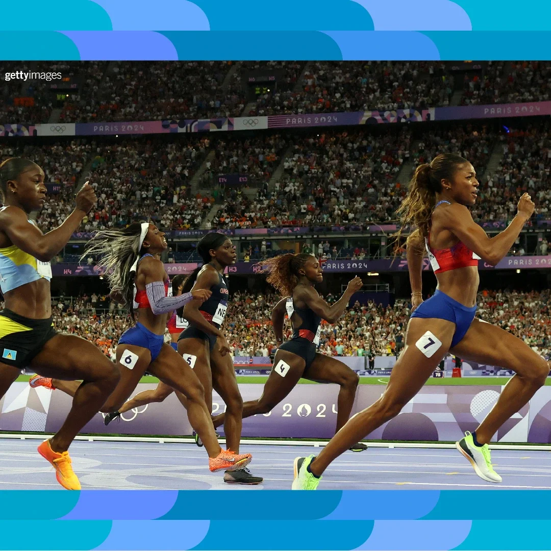 Fotografía de atletas de atletismo corriendo a toda velocidad en una pista